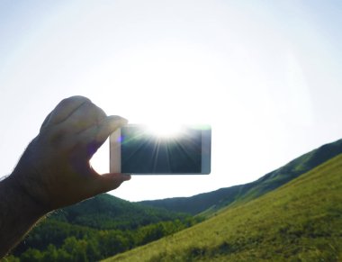 Akıllı telefon ve mavi gökyüzü. erkek eli boş ekranlı akıllı telefon tutarak. 