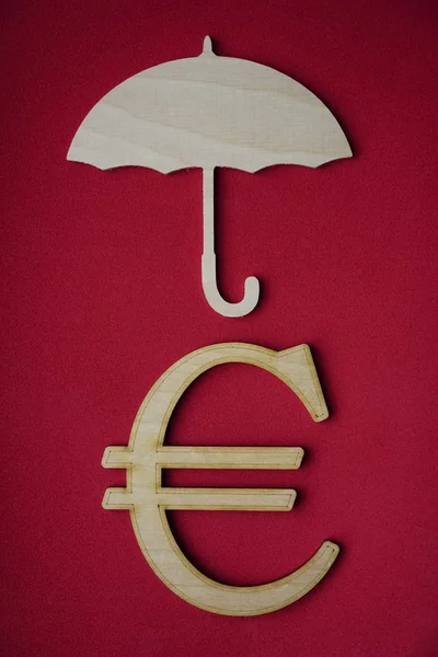 umbrella above euro sign isolated on red background. Rain of currencies.