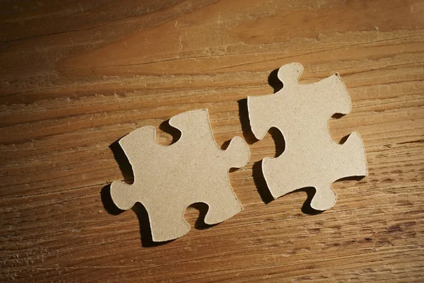 two  wooden puzzle pieces  on table. concept of connection people