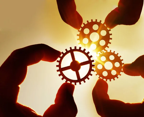 hands holding  metal gears  - sky background. business, interaction, teamwork idea