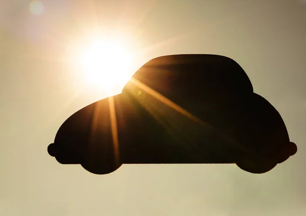 wooden car figure, sign against yellow sky background with sun rays