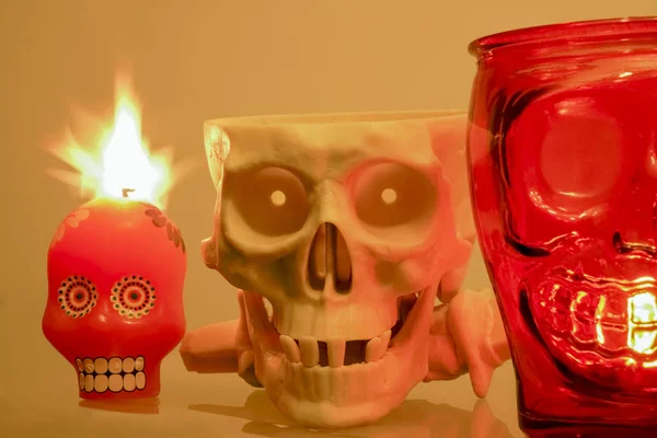 Still life with human skulls, Halloween orange candle  on yellow background