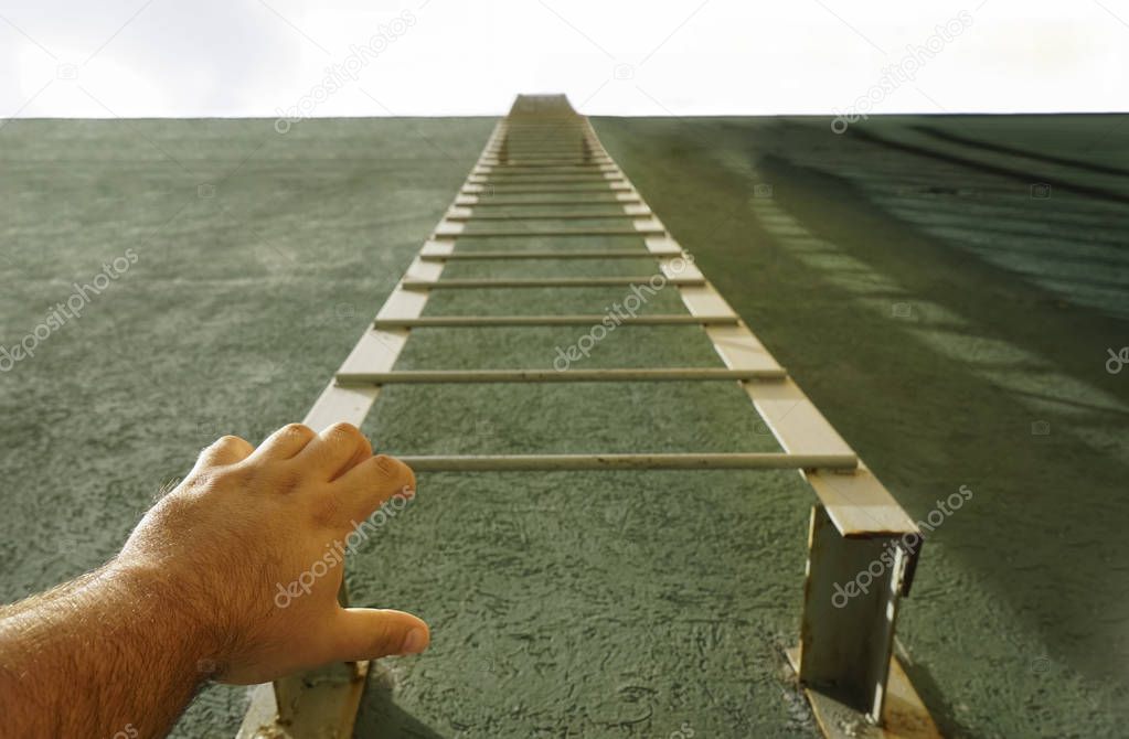 male hand reaching metal stairway on green house