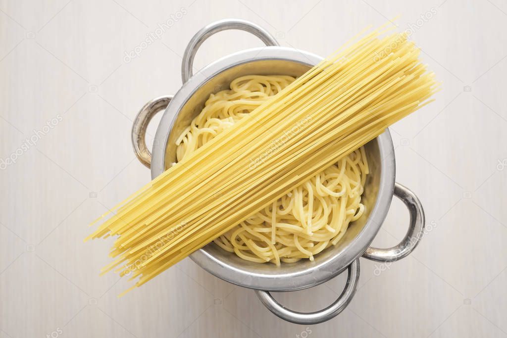 top view of italian dried and boiled noodles on white wooden table background
