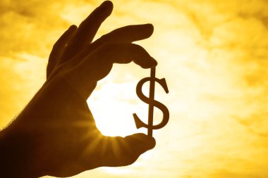 Dolar işareti silüeti gökyüzü arka plan tutan el