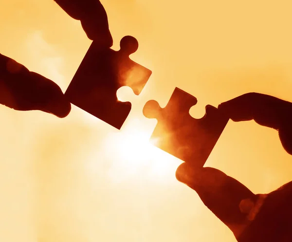 hands  with  puzzle pieces with sky background.