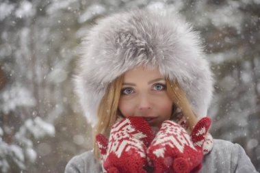 kürk kış kürk şapka, kırmızı mittens ormanda sarışın kadın portresi kapatın