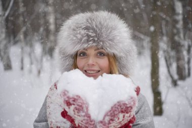 Kalp şeklinde kar. kar karlı kış ormanda üfleme kış kürk şapka neşeli sarışın kadın. Sevgililer günün kutlu olsun 