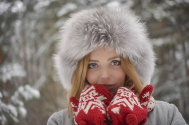 kürk kış kürk şapka, kırmızı mittens ormanda sarışın kadın portresi kapatın