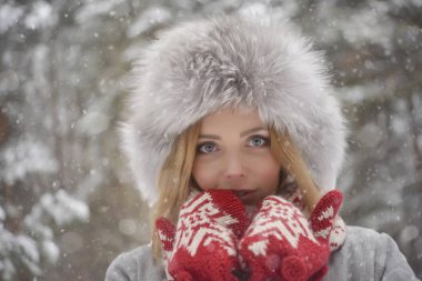 kürk kış kürk şapka, kırmızı mittens ormanda sarışın kadın portresi kapatın