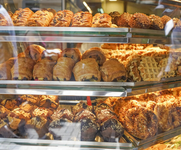view on bakery counter with many different cakes, sandwiches and bread displayed