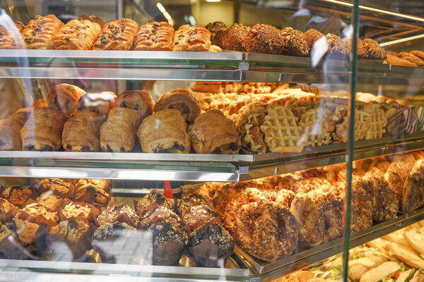 view on bakery counter with many different cakes, sandwiches and bread displayed