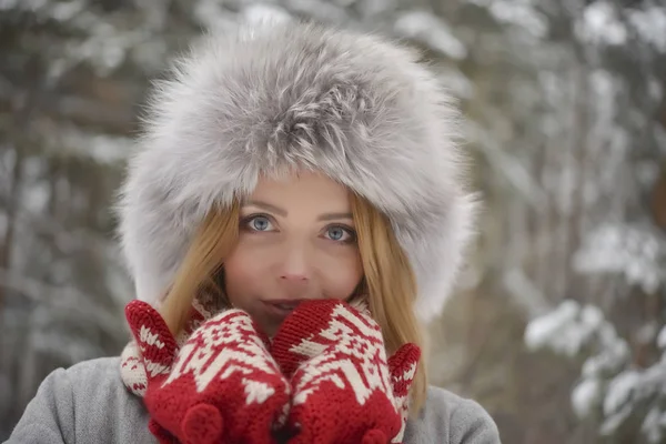 kürk kış kürk şapka, kırmızı mittens ormanda sarışın kadın portresi kapatın