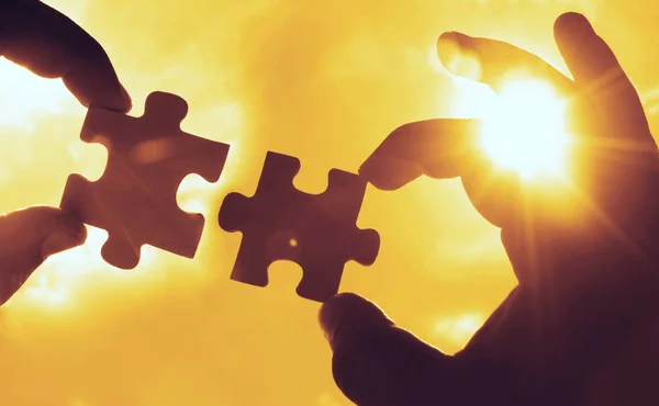 hands  with  puzzle pieces with sky background.