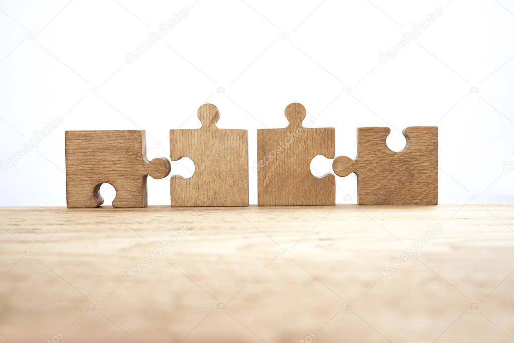  four wooden puzzle pieces   isolated on white  wall background. concept of connection people