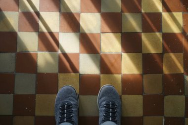 Merdivenlerde seramik tuğladan yapılmış bir çift spor ayakkabıyla duran genç adam..