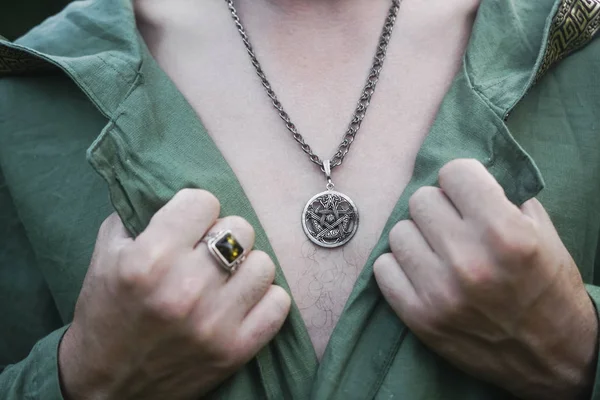 pentagram pendant on the chest of a man. ring on male finger. close up