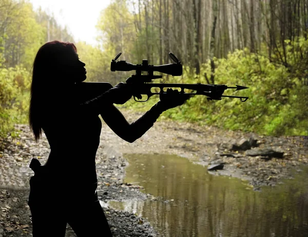 silhouette of woman shooting with bow and arrow.