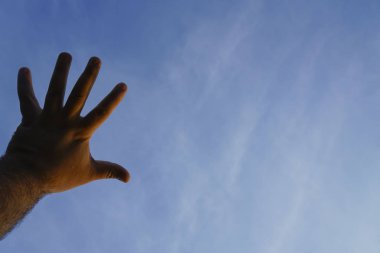 Bir erkek el mavi gökyüzünde