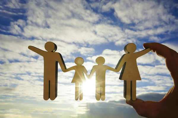 erkek el güneş ışınları ile mavi, sarı gökyüzü arka plan karşı ahşap aile işareti tutan