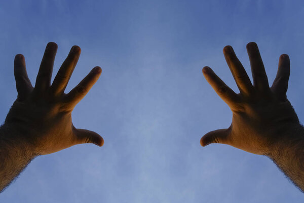 two male hands up on blue sky 