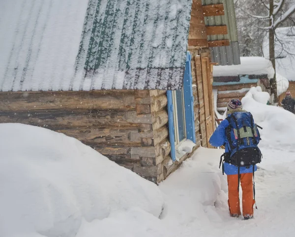 Girl backpacker by  a wooden house  on the porch.