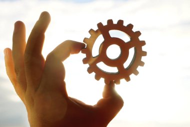 Beyaz arka plan üzerinde izole bir ahşap dişli tekerlek tutan erkek el. 