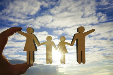 erkek el güneş ışınları ile mavi, sarı gökyüzü arka plan karşı ahşap aile işareti tutan