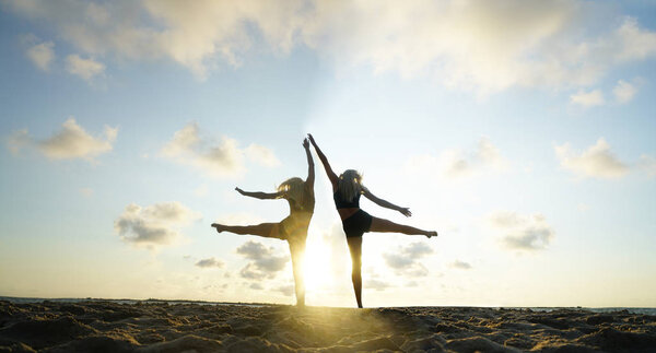 women doing exercise on summer sunny beach.