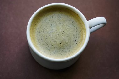 bir kahve beyaz Kupası en iyi görünümü izole kahverengi zemin üzerine siyah kahve. 