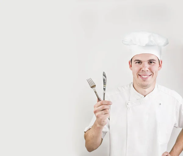 白い背景に孤立したナイフとフォークを持つスライム若いシェフの男 スマイリーフェイス 幸せな料理人男性は白いユニフォームを着用 — ストック写真