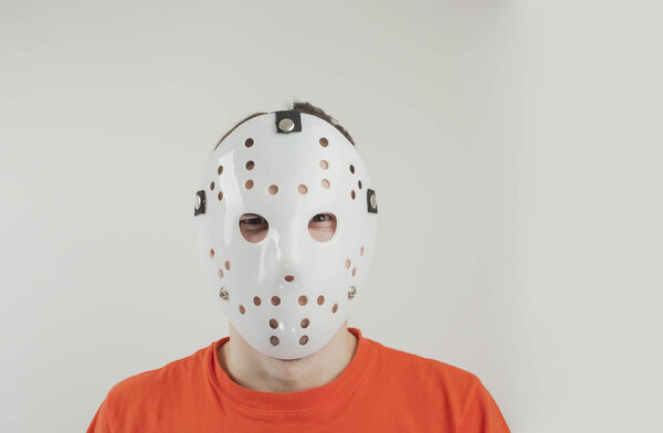 Scary hockey white mask on young man isolated on white background. Close up portrait