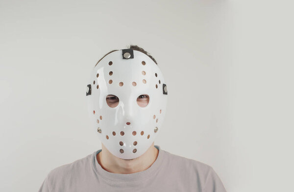 Scary hockey white mask on young man isolated on white background. Close up portrait
