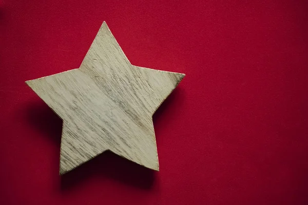 one wooden star on red background. empty copy space for inscription.