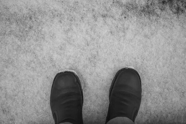 Black leather boots  on  snow background. top view. winter season. 