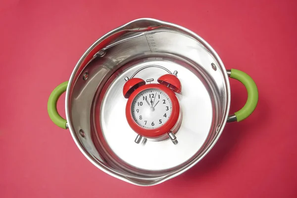 底に赤い目覚まし時計を持つ新しいソースパン 赤い背景に隔離 — ストック写真
