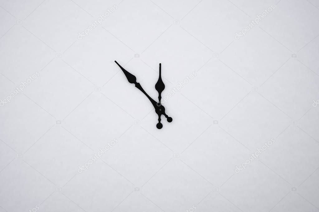hands of the clock show five to twelve and on white snow background.