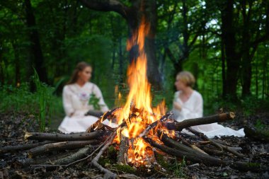 Ateşe odaklan. Akşam ormanında ateşin yanında oturan iki cadı. 