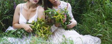 kızı kız vahşi bahar çiçekleri tutan ve yeşil çim çayır üzerinde oturan anne. yüz yok. 