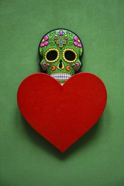 colorful skull on green background. Halloween photo, image with colorful mexican skull and red heart.  clipart