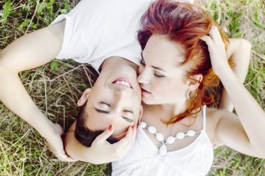 Seven çift yan yana baş yaz aylarında yeşil çimenlerin üzerinde yatarken genç. Aile pikniği. 