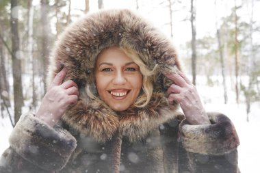 Orta yaş gülümseyen kadın kahverengi kış ormandaki açık havada manzarayı kat aşağı kapüşonlu giyiyor. 