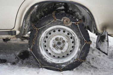 Winter chains on car wheel to drive on snowy road.