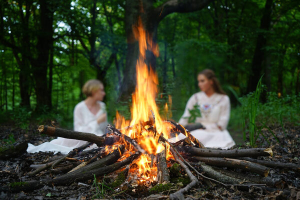 Сосредоточься на пламени. две ведьмы сидят у костра в вечернем лесу 