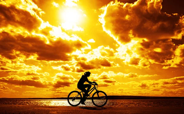 雲と太陽光線と夕日の空に対してバイクでスポーティな観光女性 — ストック写真
