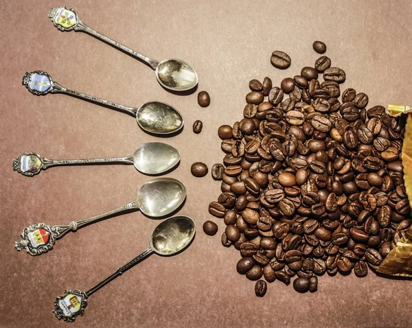 コーヒー豆の周りの多くのビンテージ スプーン 茶色の背景に分離 — ストック写真