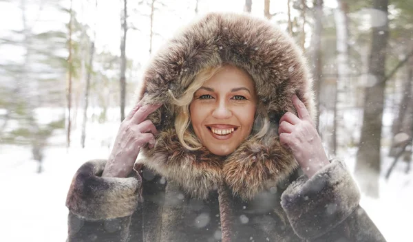 中年微笑的妇女穿着棕色头套下来外套欣赏在冬季森林户外的看法 — 图库照片