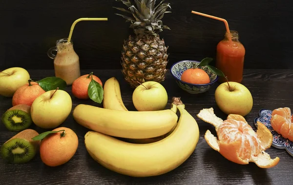 two Glass bottles of fruit juice on black wooden table