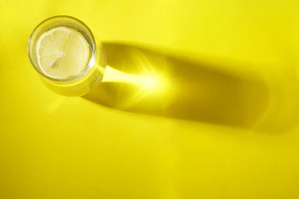 Vaso Con Rodaja Limón Vista Superior Sombra Sobre Fondo Amarillo — Foto de Stock