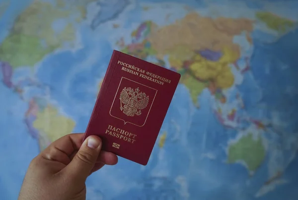 Russian passport for traveling abroad on the world map background.  hand holding  red international passport
